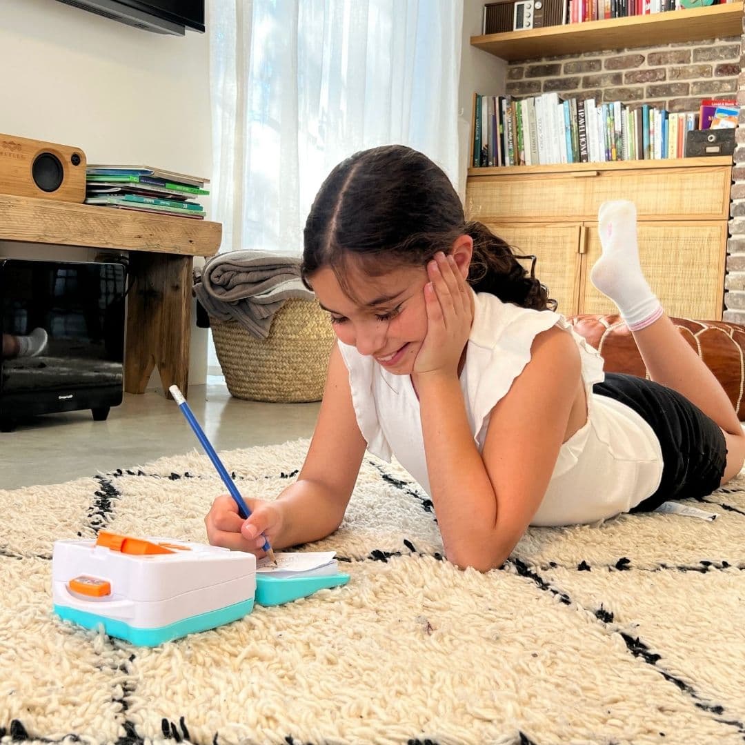 ילדה מציירת באמצעות מקרן חכם לדרך !smART Sketcher® GO תוך כדי שכיבה על שטיח בבית