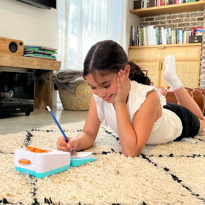 ילדה מציירת באמצעות מקרן חכם לדרך !smART Sketcher® GO תוך כדי שכיבה על שטיח בבית